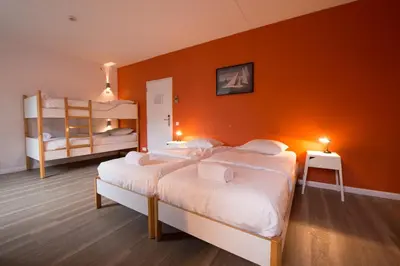 a bedroom with two bunk beds and an orange wall at Auberge des 3 Fontaines - Youth Hostel in Brussels