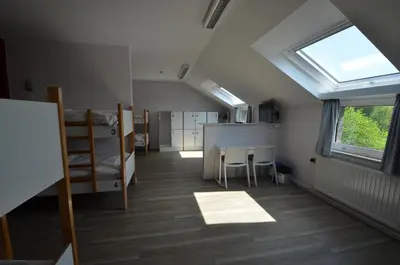 a dorm room with a window and a table and chairs at Auberge des 3 Fontaines - Youth Hostel in Brussels