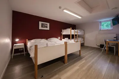 a bedroom with a large bed with white sheets at Auberge des 3 Fontaines - Youth Hostel in Brussels