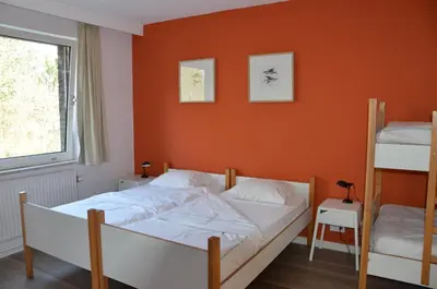 a bedroom with a bed with an orange wall at Auberge des 3 Fontaines - Youth Hostel in Brussels