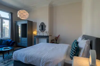 a bedroom with a white bed and a blue chair at Garden of Eden in Antwerp