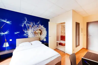 a bedroom with a large white bed and a blue wall at Hotel Soret in Overijse