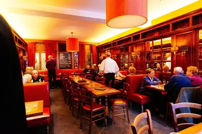 a group of people sitting at tables in a restaurant at Hotel Soret in Overijse