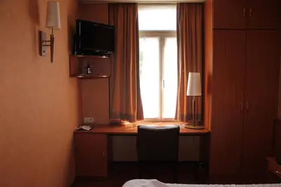 a room with a desk with a television and a window at Hotel De Notelaer in Bornem