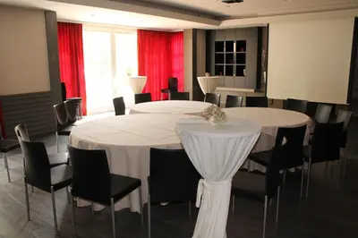 a room with two tables and chairs and red curtains at Hotel De Notelaer in Bornem
