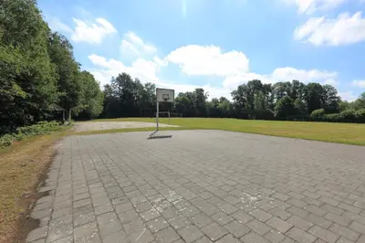an empty basketball court with a basketball hoop in a park at Camping Baalse Hei in Turnhout