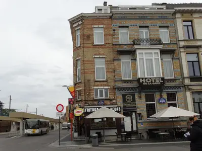 a building on the corner of a street with a bus at Hotel de la Gare Aalst in Aalst