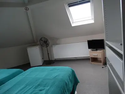 a room with two beds and a fan and a window at Hotel de la Gare Aalst in Aalst