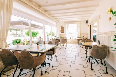 a restaurant with tables and chairs and windows at Hotel De Kalvaar in Ninove