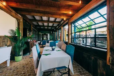 a dining room with a table and chairs and windows at Hotel De Kalvaar in Ninove