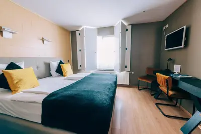 a hotel room with a large bed and a desk at Hotel De Kalvaar in Ninove