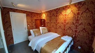 a bedroom with a bed and a wall with wallpaper at Bosdam Budget Rooms in Beveren