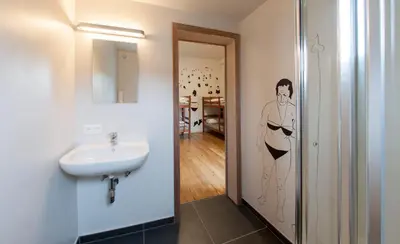 a bathroom with a sink and a painting of a woman at KaBa Hostel in Ghent