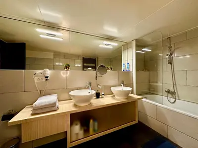 a bathroom with two sinks and a shower and a tub at Luxury Suites Castel by Rikas Hotels in Antwerp