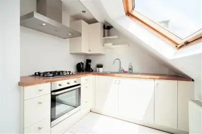 a kitchen with white cabinets and a skylight at Beautiful Cozy Apartments in the Heart of Antwerp in Antwerp