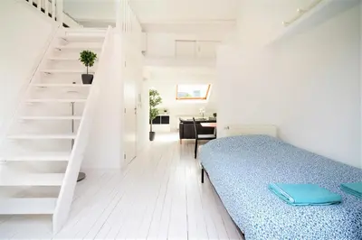a white room with a bed and a staircase at Beautiful Cozy Apartments in the Heart of Antwerp in Antwerp