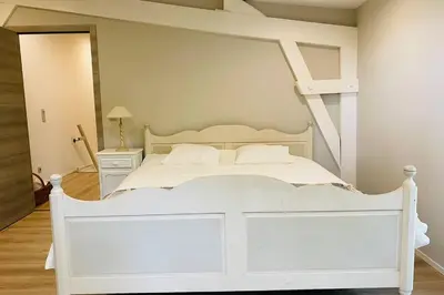 a bedroom with a white bed with a ladder at Cosy house in a charming village in Beauvechain