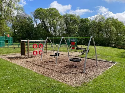 a park with a playground with two swings at Cosy house in a charming village in Beauvechain