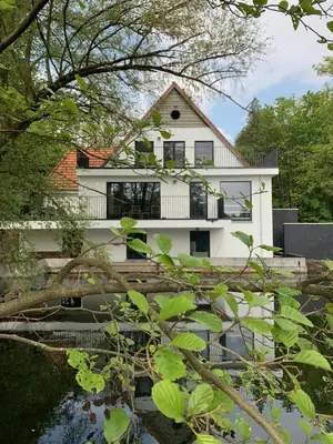 a white house with a pond in front of it at Vakantiehuis Ochtendgloren in Turnhout