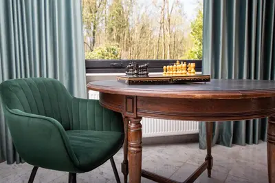 a wooden table with a green chair next to a window at Vakantiehuis Ochtendgloren in Turnhout