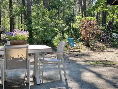 two chairs and a table in a garden with flowers at Boshuisje in Lille