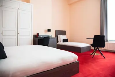a bedroom with two beds and a desk and a table at La Bourse Hotel in Brussels