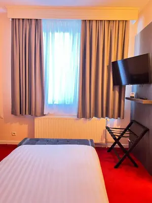 a hotel room with a bed and a flat screen tv at La Bourse Hotel in Brussels