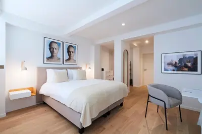 a white bedroom with a bed and a desk at THE GOOD FLATS in Brussels