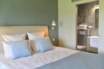 a bedroom with a bed with blue and white pillows at B&B Entre Champs in Ohain