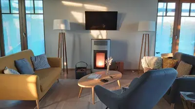 a living room with a fireplace with chairs and a table at B&B Entre Champs in Ohain