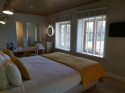 a bedroom with a bed and a table and windows at B&B Entre Champs in Ohain