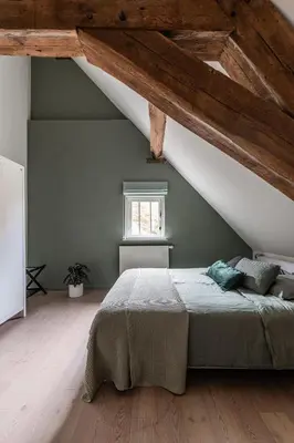 a bedroom with a large bed in a attic at Beddermolen - Molenhuis op historisch erfgoeddomein in Westerlo