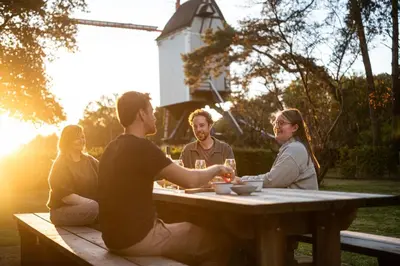 a group of people sitting around a picnic table at Beddermolen - Molenhuis op historisch erfgoeddomein in Westerlo