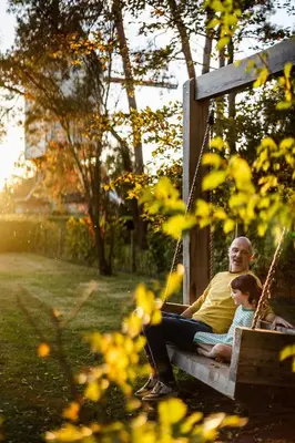 a man and a child sitting in a swing at Beddermolen - Molenhuis op historisch erfgoeddomein in Westerlo