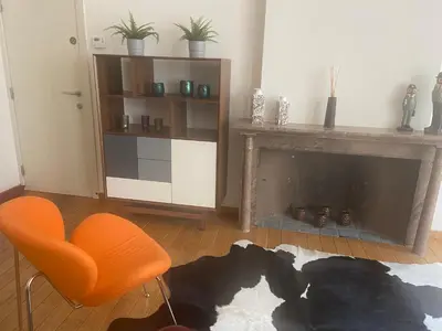 a living room with an orange chair and a fireplace at Ghent Centre Croft Deluxe in Ghent