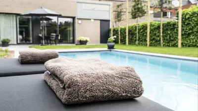 a pair of ottomans sitting next to a swimming pool at Guesthouse Max in Burcht