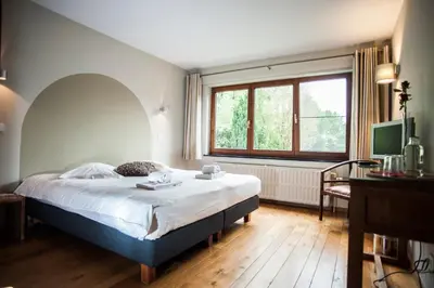 a bedroom with a large bed and a window at B&B De Meren in Aarschot