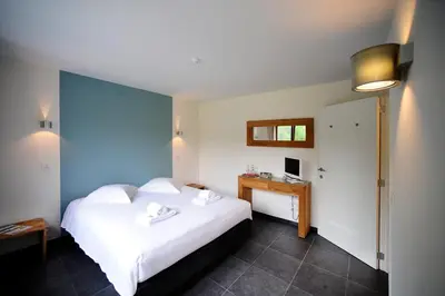 a bedroom with a large white bed and a desk at B&B De Meren in Aarschot