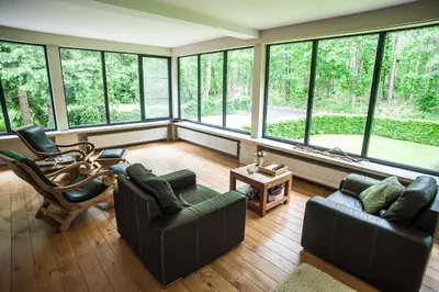 a living room filled with furniture and large windows at B&B De Meren in Aarschot