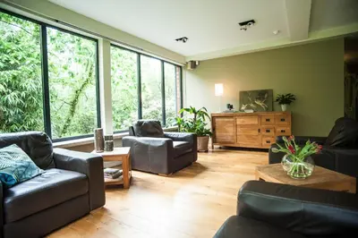 a living room with leather furniture and large windows at B&B De Meren in Aarschot