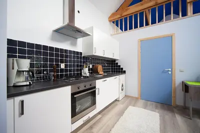 a kitchen with white cabinets and a blue door at B&B t'Keygoed in Ghent