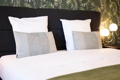 a bed with white sheets and pillows in a bedroom at B&B De Koepoort in Mechelen