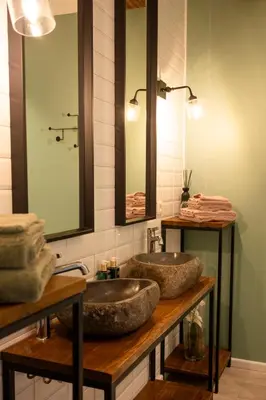 a bathroom with a stone sink and two mirrors at B&B De Koepoort in Mechelen
