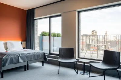 a bedroom with a bed and chairs in front of a window at Citybox Antwerp City Center in Antwerp