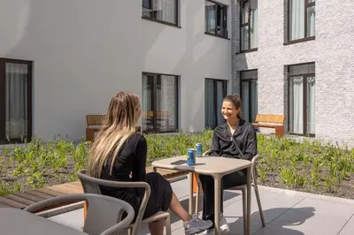 two women sitting at a table in front of a building at Citybox Antwerp City Center in Antwerp