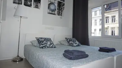 a bedroom with a bed with blue sheets and pillows at Roosevelt Apartments. in Antwerp