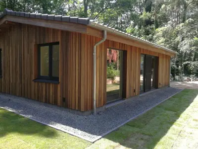 a small wooden building with windows in a yard at Hogenberg Heiken Lichtaart Kasterlee met eigen laadpaal in Lichtaart