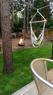 a hammock hanging from a tree next to a fire at Hogenberg Heiken Lichtaart Kasterlee met eigen laadpaal in Lichtaart