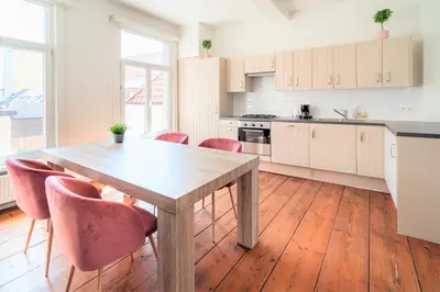 a kitchen with a wooden table and pink chairs at Antwerp Old Town Centrum Apartment in Antwerp