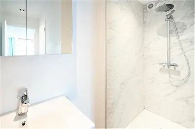 a white bathroom with a shower and a sink at Saint Pauls Central Residence in Antwerp